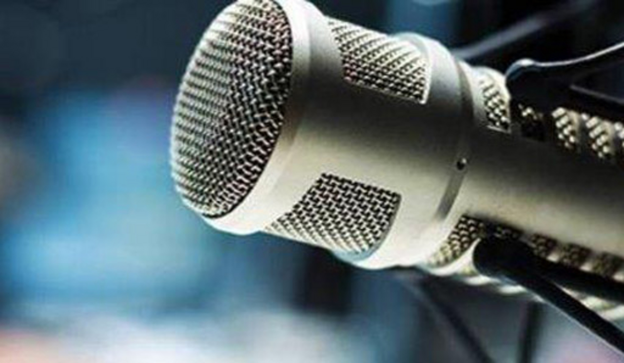 Mikrofon im Vordergrund mit blauem, unscharfem Hintergrund